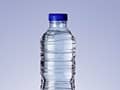 Klare Plastik-Wasserflasche mit blauem Deckel vor neutralem Hintergrund.